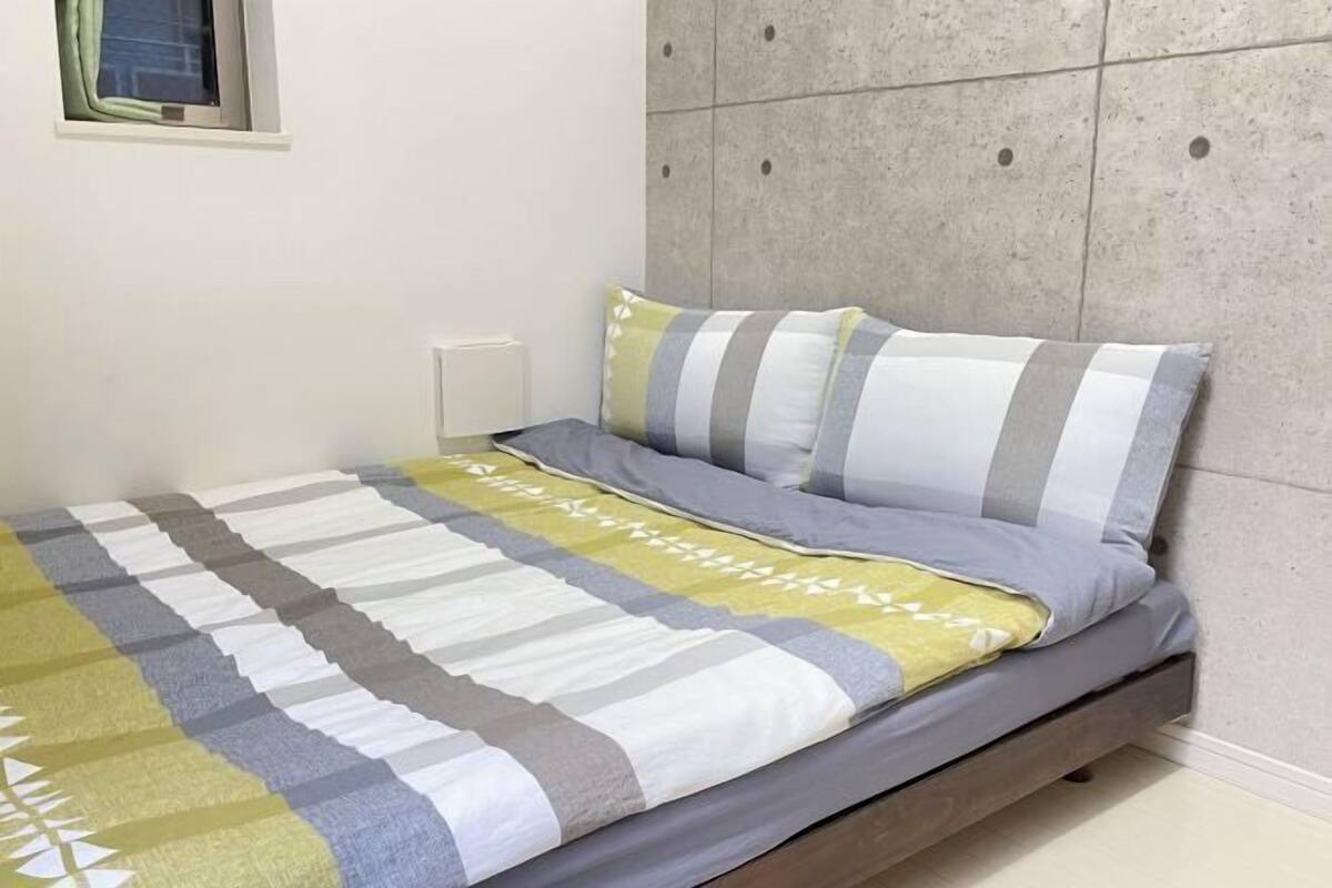 A bedroom with a bed, a window, and a wall with a textured panel design.