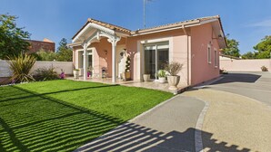 A single-story house with a tiled roof, a covered porch, and a well-maintained lawn.