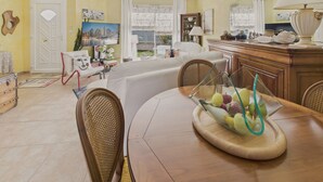 A dining area with a wooden table, wicker chairs, and a fruit bowl.