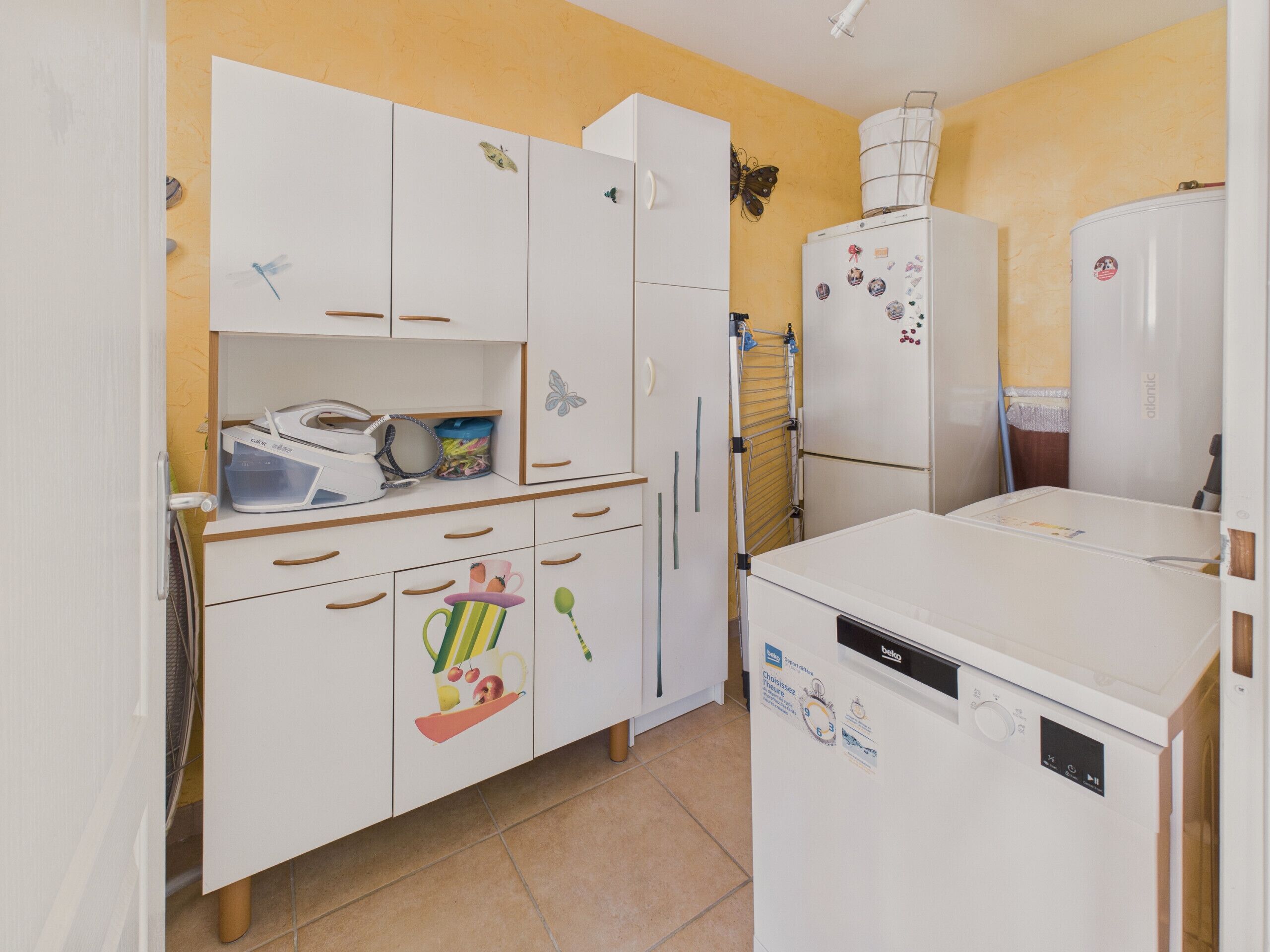 Uma cozinha compacta com armários brancos, lava-louças e frigorífico.
