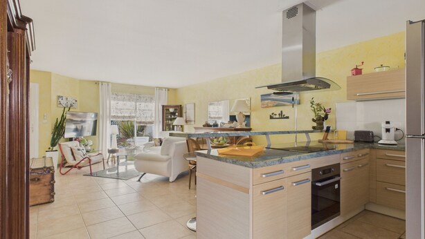 A modern kitchen with a central island, built-in appliances, and a dining area with a sofa and chairs.