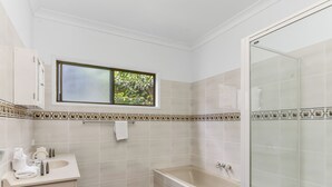 A bathroom with a window, a bathtub, a shower, and a sink. - Hillcrest Retreat with River Views (Tweed Heads South)