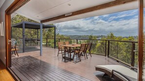 A wooden deck with a table and chairs, a pergola, and a view of the landscape. - Hillcrest Retreat with River Views (Tweed Heads South)