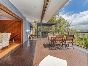 A wooden deck with a table and chairs, a covered area, and a view of the surrounding landscape. - Hillcrest Retreat with River Views (Tweed Heads South)