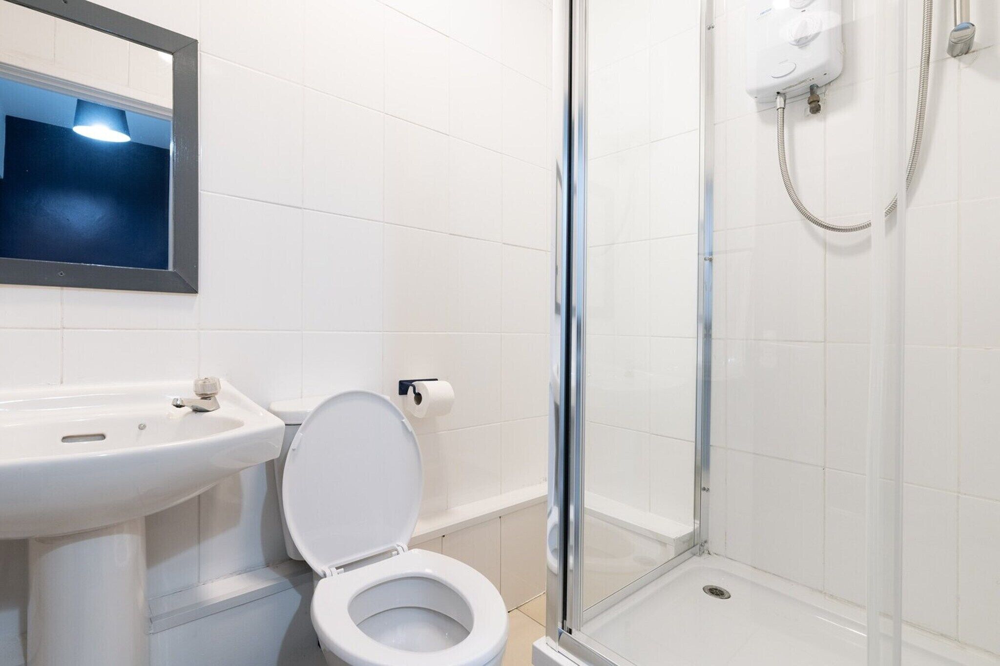 Een badkamer met een witte wastafel, toilet en douchecabine met glazen wanden.