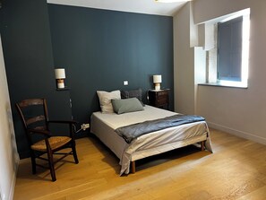 A bedroom with a bed, two bedside tables, a chair, and a window. - MAISON GALLY (Carcassonne)