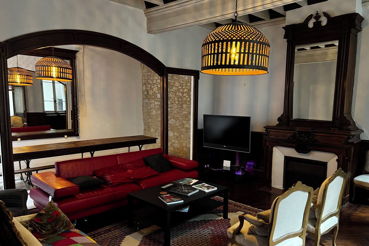 A living room with a red sofa, black coffee table, and a TV. There is a fireplace and a mirror on the wall.