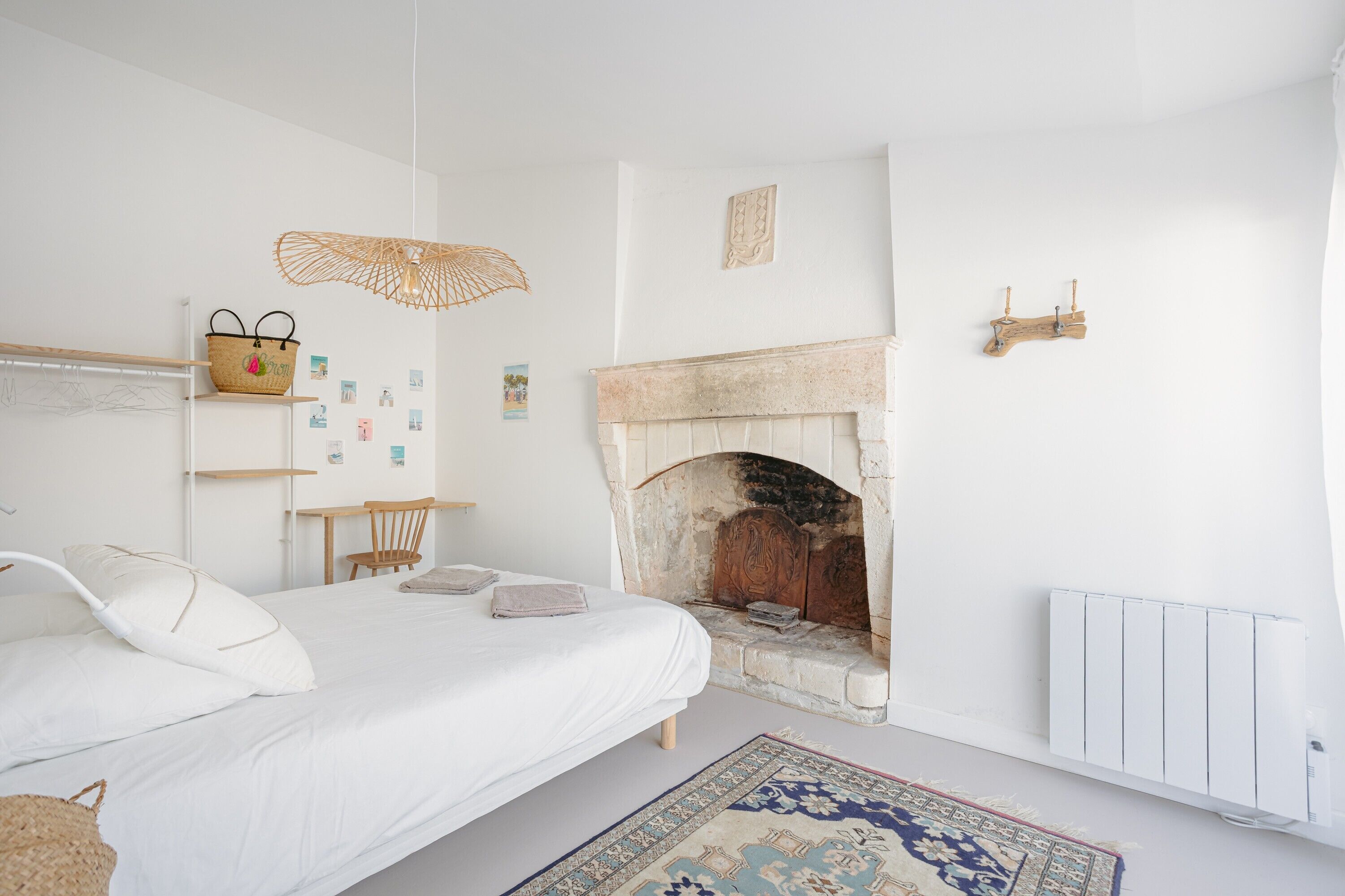 Une chambre à coucher avec un lit, une cheminée, un radiateur et un panier en osier posé sur une étagère.