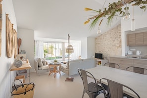 A modern kitchen with a dining area, large windows, and a stone wall.