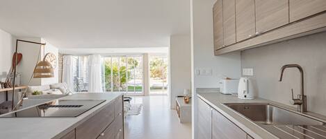 Une cuisine moderne dotée d’un grand îlot central, de meubles de rangement intégrés et offrant une vue sur l’extérieur.