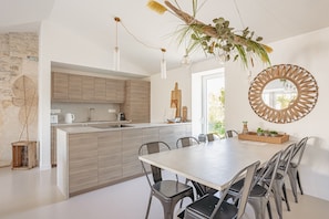 A modern kitchen with wooden cabinets, a central island, and a dining area with chairs.