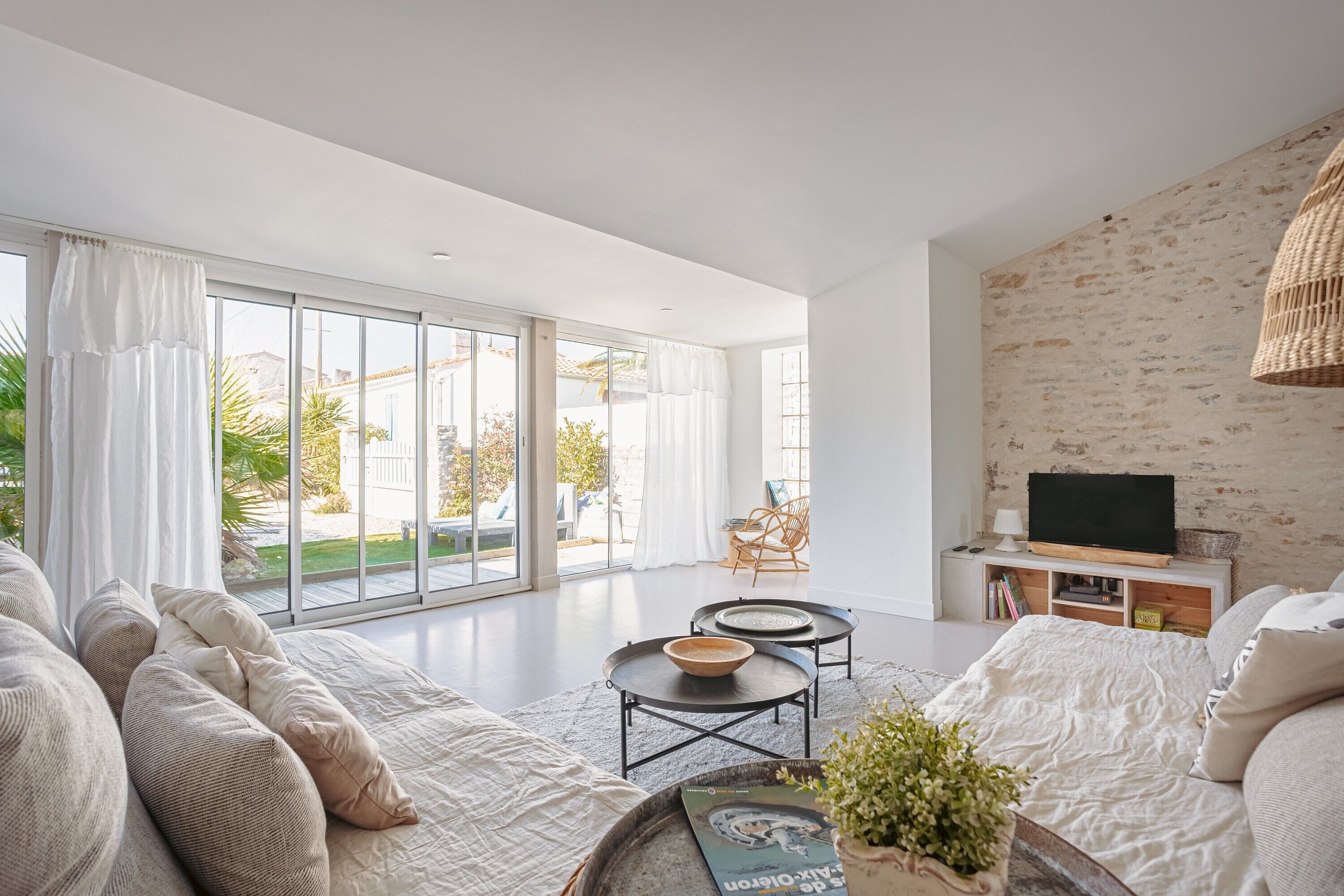 A modern living room with a sofa, two round tables, a television, and a bookshelf.