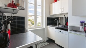 Eine moderne Küche mit schwarzer Arbeitsplatte, weißen Schränken, einem Fenster und einem roten Wasserkocher.
