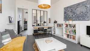 Ein modernes Wohnzimmer mit Sofa, Couchtisch, Essbereich, Bücherregal und einer großen Wandkarte.