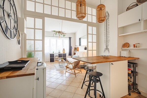 A modern kitchen with a wooden countertop, bar stools, and a large window.