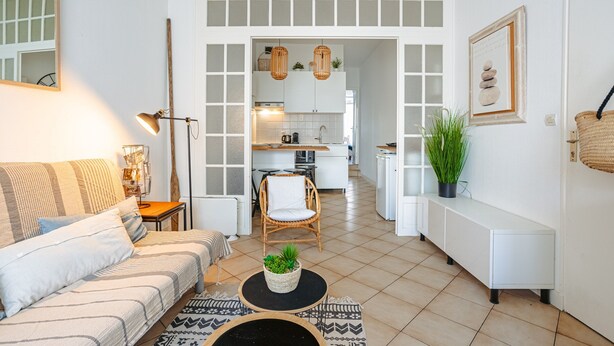 Un salon avec un canapé, une table basse, une lampe et une vue sur la cuisine.
