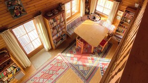 Interior de una cabaña de madera con habitación en altillo, comedor y biblioteca.