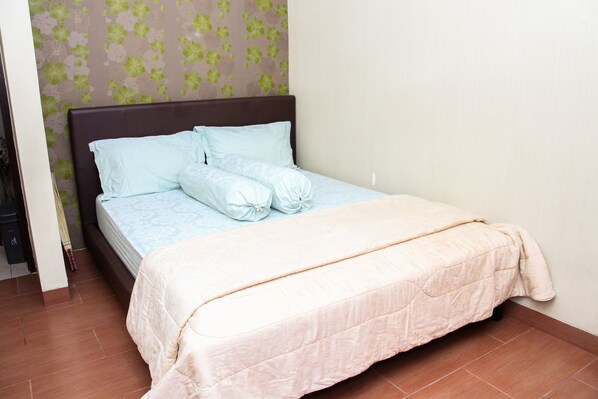 A neatly made bed with a light-colored bedspread and pillows, a dark headboard, and a floral-patterned wall. - Aldeoz Villa Dago Pakar Bandung (Cimenyan)