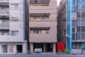 Un edificio residencial de varios pisos con un coche estacionado en el garaje.