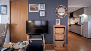 A living room with a TV, a sofa, a coffee table, and a kitchen in the background. - Sumida Midori APT (Tokyo)
