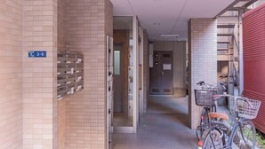 A corridor with tiled walls, a bicycle, and a red building on the right. - Sumida Midori APT (Tokyo)