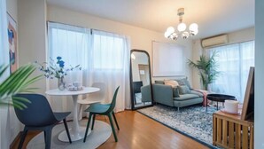 A living room with a round table, two chairs, a sofa, a mirror, and a small table with a plant. - Sumida Midori APT (Tokyo)