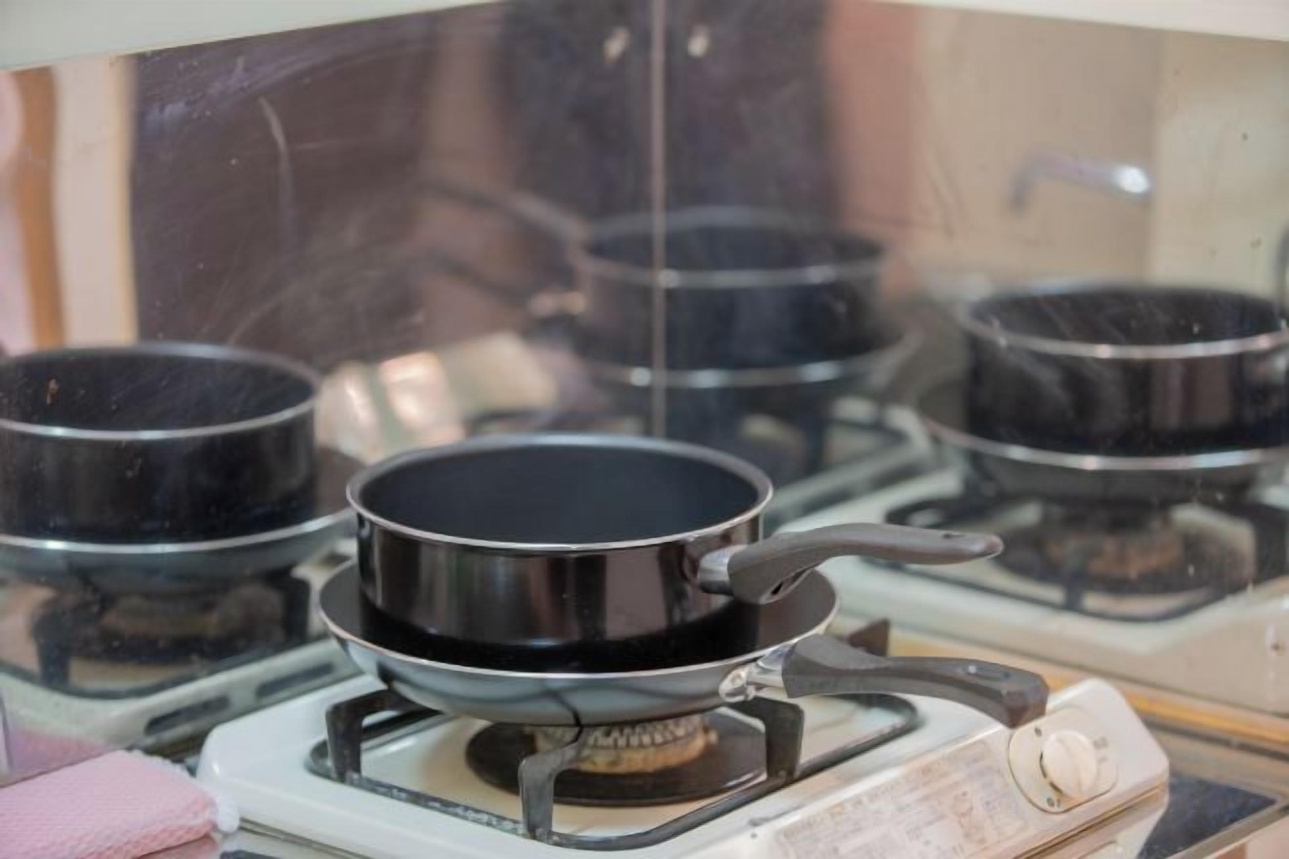 Una cocina con estufa a gas, una sartén y una olla sobre las hornillas.