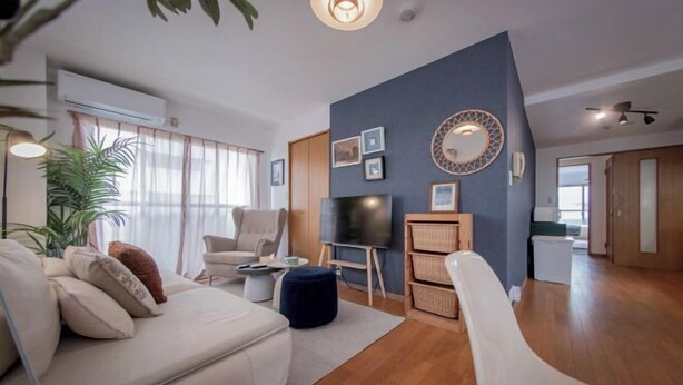 A modern living room with a sofa, armchair, TV, and a decorative wall. - Sumida Midori APT (Tokyo)