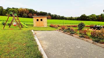 A gravel path leading to a wooden structure, a swing set, and a small shed in a landscaped area.