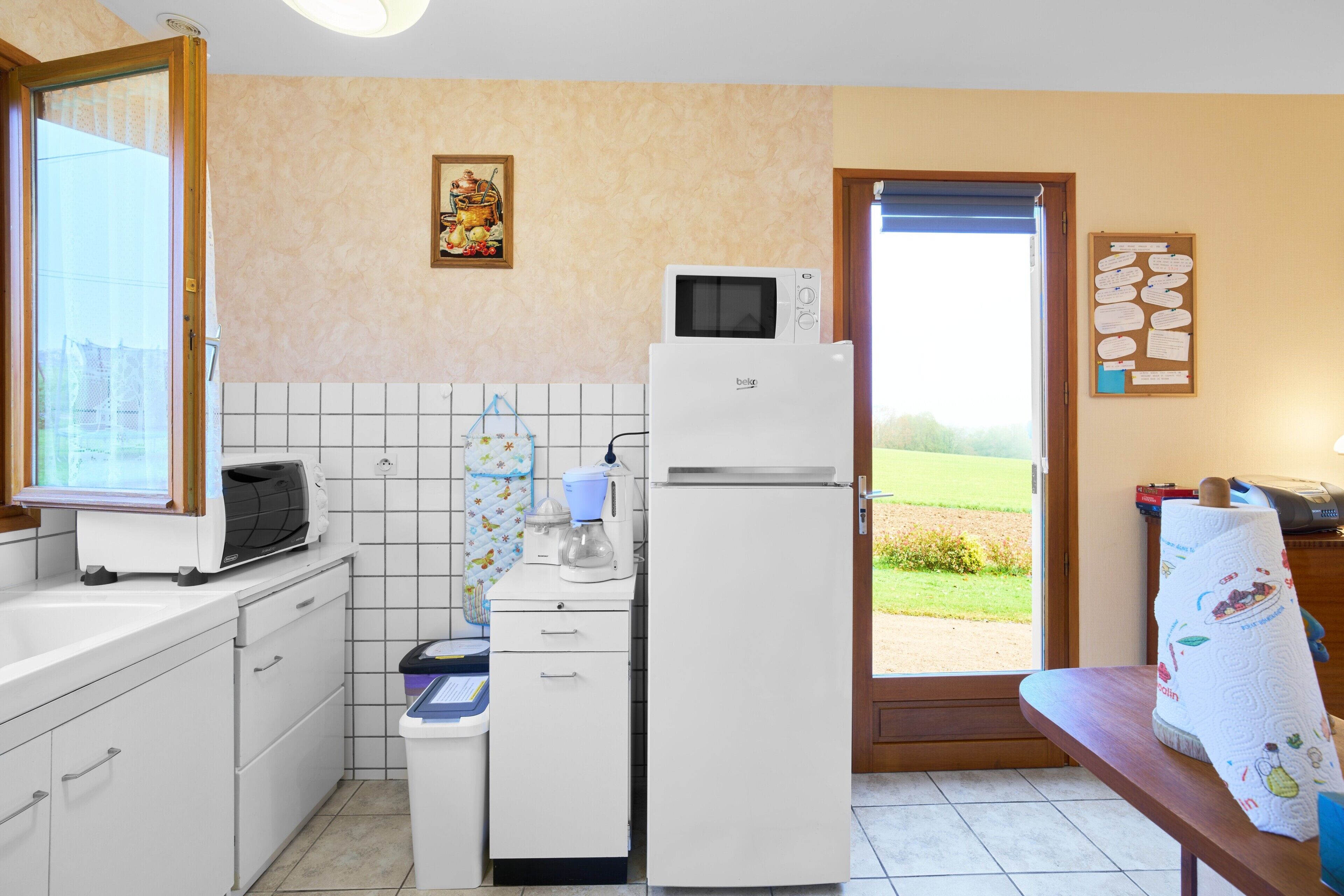 A kitchen with a microwave, refrigerator, and a window to the outside.