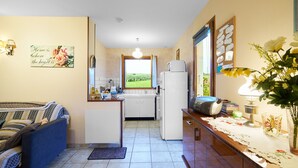 Une cuisine compacte avec vue, un coin repas avec un canapé et une petite table avec une lampe.