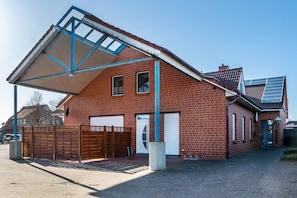A red brick building with a sloped roof, a covered entrance, and a solar panel on the roof. - Apartment 'Kirschner's 1' with Shared Terrace and Wi-Fi (Horumersiel-Schillig)