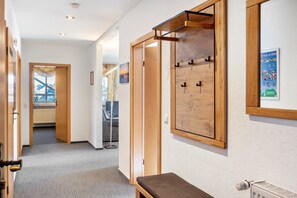 Un couloir avec des portes en bois, un banc et un radiateur.