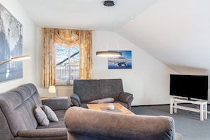 A modern living room with a sofa, a coffee table, a TV, and a painting on the wall. - Apartment 'Kirschner's 2' with Shared Terrace and Wi-Fi (Horumersiel-Schillig)