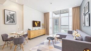 Een moderne woonkamer met een bank, stoelen, een eettafel, een televisie en een groot raam met gordijnen.