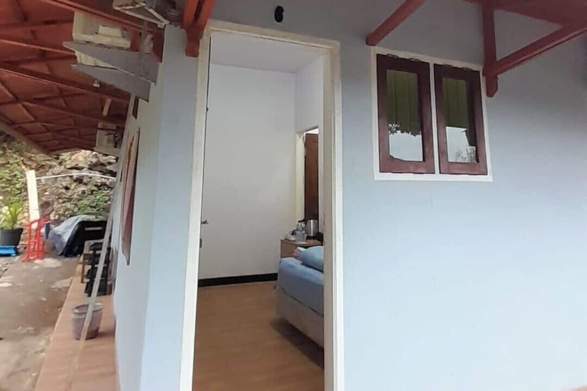 Un porche cubierto con techo de madera, una cama y una pequeña planta en maceta.