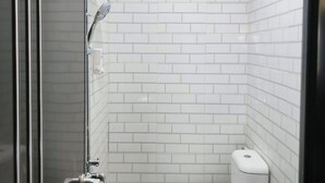 A small, white-tiled bathroom with a shower, toilet, and bidet. - Pondok Indah At Teluk Asmara Beach (Sitiardjo)