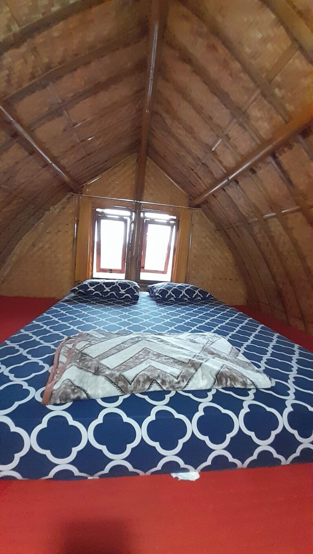 A small, cozy attic bedroom with a sloped ceiling and two windows.