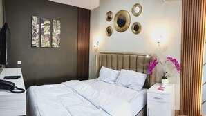 A hotel room with a bed, bedside table, lamp, and artwork on the wall. - Pondok Indah At Teluk Asmara Beach (Sitiardjo)