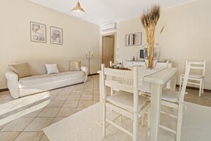 A living room with a sofa, dining table, chairs, a vase, and artwork on the walls. - Casa di Lisa Villasimius (Villasimius)