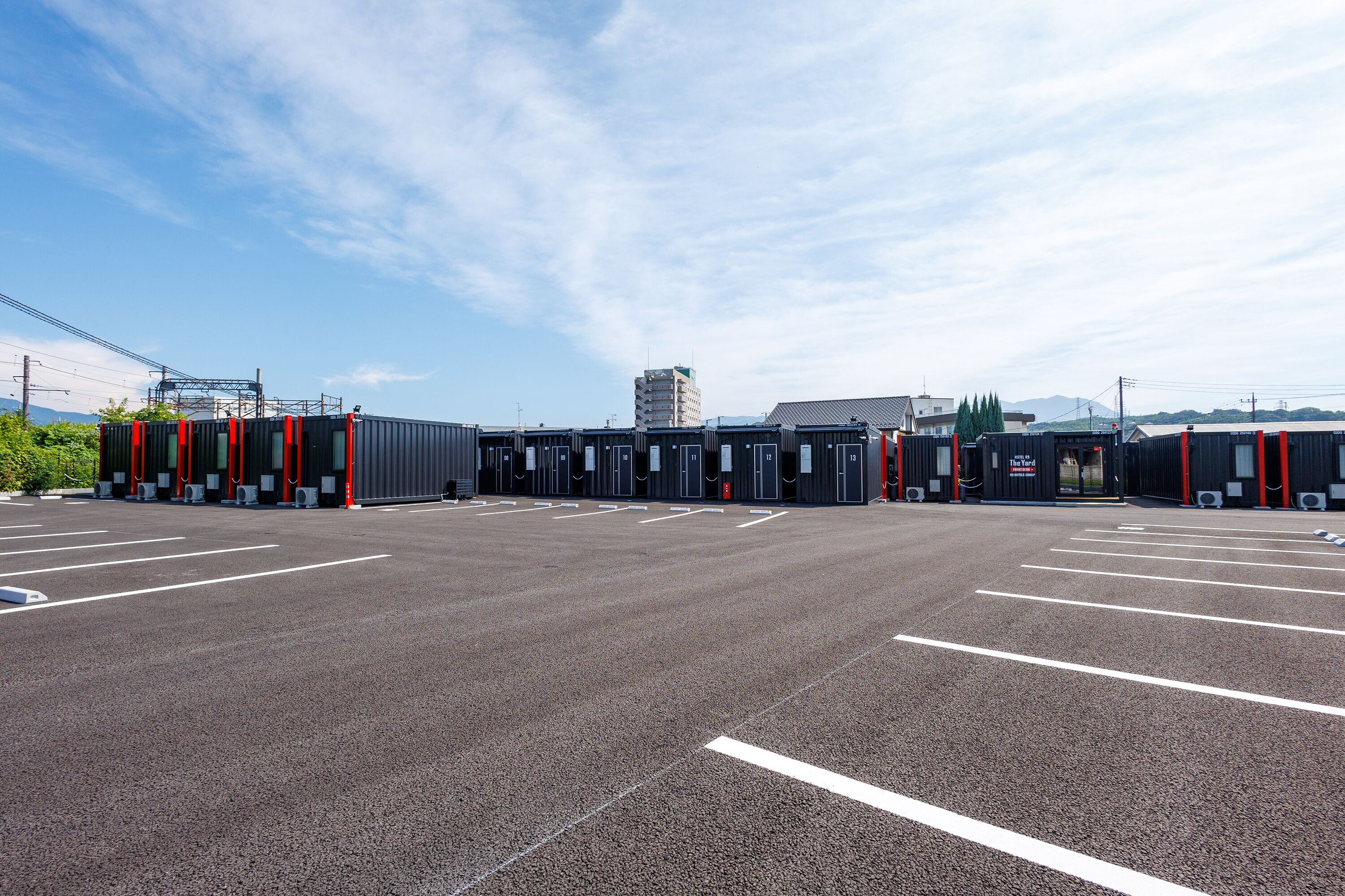 A parking lot with multiple rows of parking spaces and a building with a red and black facade in the background.