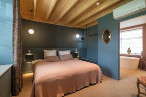 Un dormitorio con una cama grande, mesitas de noche, un espejo y una ventana con vistas.