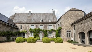 A historic stone building with a symmetrical facade, multiple windows, and a central entrance. - 3 bedroom house with Jacuzzi (Hotton)