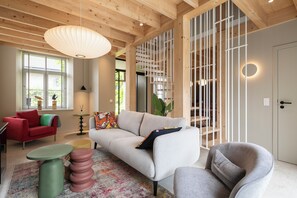 Een moderne woonkamer met een bank, stoelen, een salontafel en een decoratieve lamp.