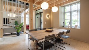 A modern dining area with a wooden table, metal chairs, and pendant lighting. - 3 bedroom house with Jacuzzi (Hotton)