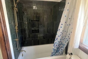 Een badkamer met een badkuip, douche en toilet.