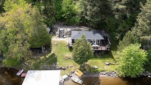 A house surrounded by trees with a dock and a small boat. - Muskoka Cabana - Sandy beach cottage in Muskoka (Utterson)
