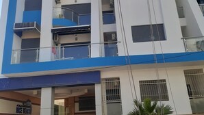 A multi-story building with balconies, air conditioning units, and a staircase leading to the entrance. - Nice apartment (Kenitra)