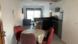 A dining area with a round table, two red chairs, and a vase with flowers. - Nice apartment (Kenitra)