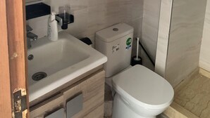 A bathroom with a sink, mirror, toilet, and a towel ring on the wall. - Nice apartment (Kenitra)